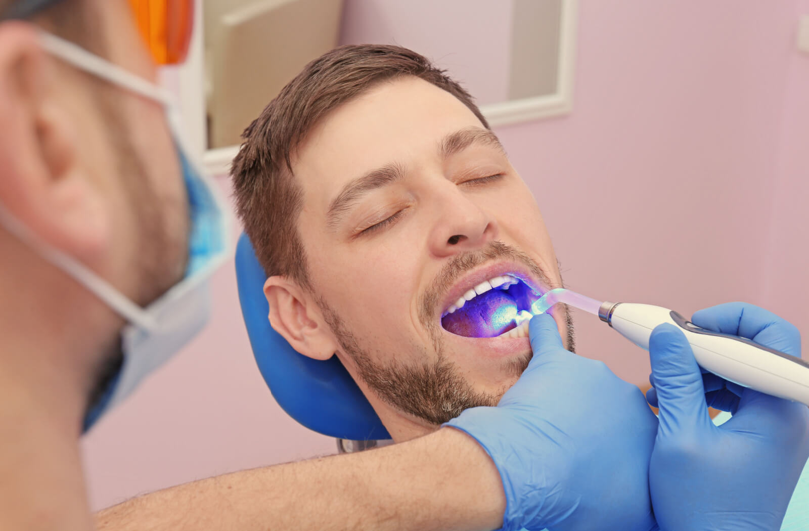 A dentist is doing a tooth filling on a male patient using alternative materials for fillings, such as composite resin, to reduce exposure to toxins.