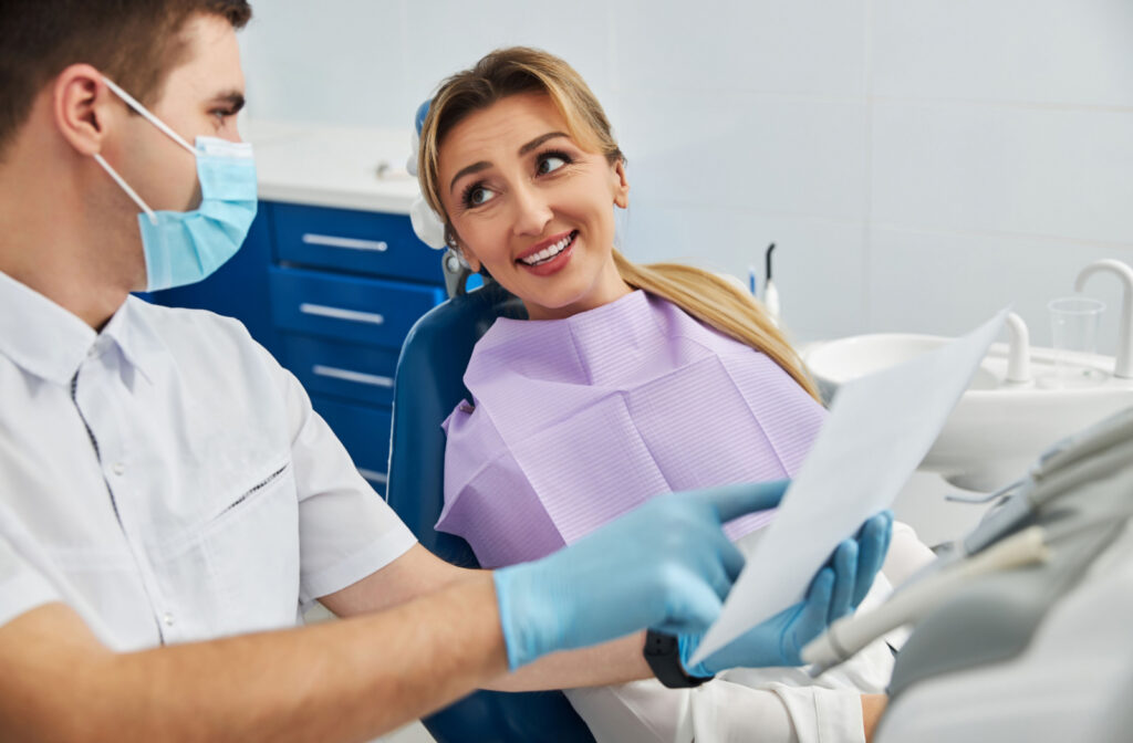 a woman sits in a dental chair speaking to a dentist about healthy teeth