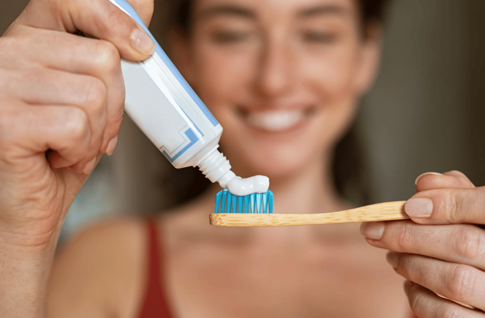 A woman puts toothpaste onto her toothbrush.
